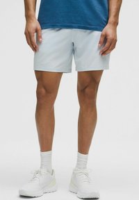 Lyseblå atletikshorts lavet af fugttransporterende stof, designet til komfort, parret med hvide sneakers og ankellange hvide sokker.
