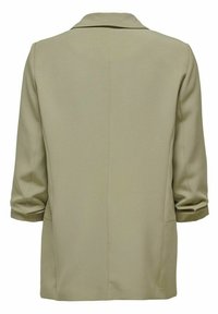 Blazer beige au design ajusté, avec un col à revers, des manches trois-quarts et des poches latérales. Texture de tissu lisse.