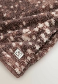 Brown and beige soft fleece fabric with a speckled pattern and a small square tag featuring a decorative logo.