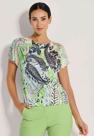 Korte mouwen blouse in lichtblauw met een groen en zwart paisleypatroon. Zachte stof met een relaxte pasvorm en ronde halslijn.