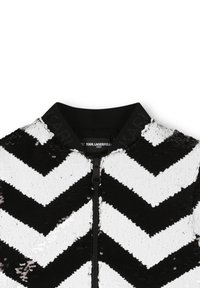 Veste bomber noir et blanc avec un motif en sequins en chevron, dotée d'une fermeture éclair et d'un col côtelé noir uni.