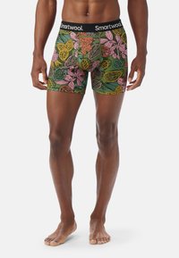 Boxer-kalsonger i grön tyg med ett färgglatt bladmönster i rosa, gult och orange. Har en svart midjeband med "Smartwool"-logotyp.