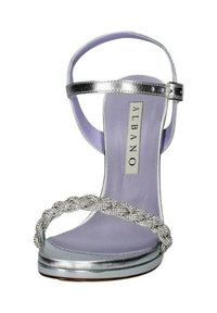 Sandalo con tacco alto in metallo argentato, con cinturino intrecciato impreziosito da strass e soletta in lilla. Cinturino alla caviglia regolabile con fibbia.