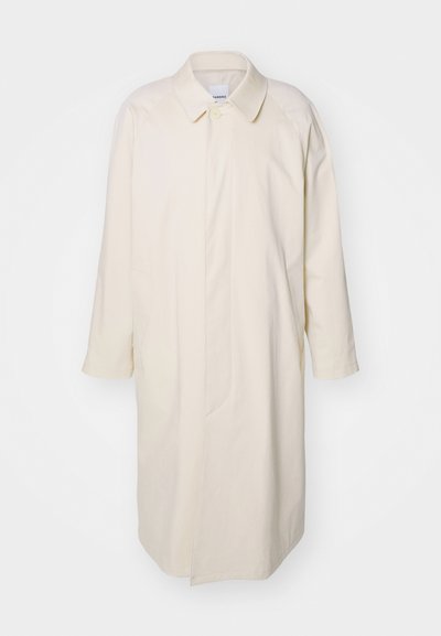 Ljusbeige knälång kappa i bomull med en avslappnad passform, som har krage, stora knappstängningar och sidofickor.