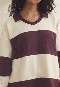 Sweatshirt met bordeauxrode en crèmekleurige strepen, een kraag met V-hals en reliëflogo in het midden. Zachte, gestructureerde stof.