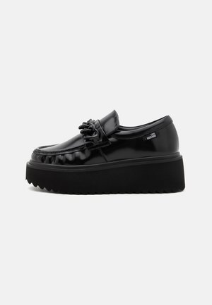 Mocassin à plateforme noire avec semelle épaisse, finition brillante, détail chaîne sur le cou-de-pied, et étiquette "Love Moschino" sur le côté.