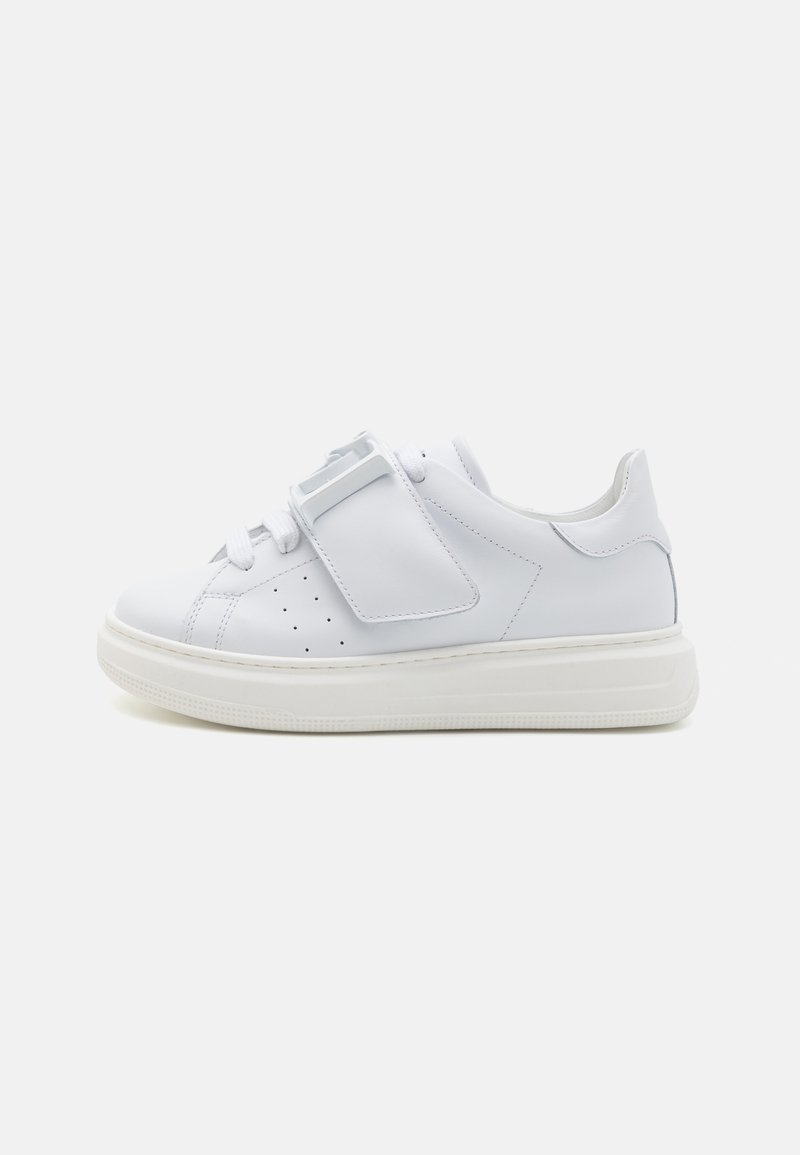 White leather sneaker with a smooth texture, featuring a flat sole, perforated design on the sides, and a prominent strap closure.