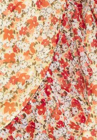 Blommig tyg har ett mönster av orange, röda och vita blommor på en gul bakgrund, med en texturerad yta och mjuk fall.