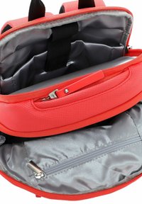 Zaino rosso con texture, interno foderato grigio, tasca con cerniera e spallacci regolabili. La borsa ha una chiusura robusta con cerniera.