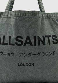 Szürke vászontáska két füllel, kiemelkedő fekete felirattal: "ALLSAINTS", japán karakterek, és "LONDON". Puha tapint�ás.