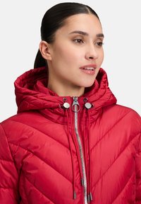 Rote Puffjacke mit Chevron-Muster, Reißverschluss, verstellbarem Kordelzugkapuze und silbernen Hardware-Akzenten. Glatte und gesteppte Textur.