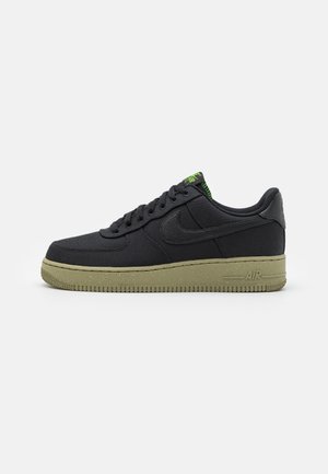 Sneaker nera low-top con tomaia in tessuto strutturato, lacci neri e suola e dettagli sul tallone maculati verde oliva.