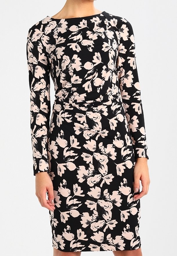 Robe noire mi-longue à manches longues avec imprimé floral rose pâle et fronces discrètes à la taille, portée par une personne sur un fond uni.