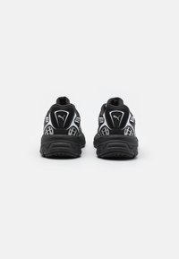 Černé sportovní boty s textilním svrškem z mřížky a reflexními prvky. Tlustá gumová podešev s protiskluzovým vzorkem, s logem na patě a bocích.