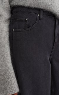 Jeans de mezclilla negra con un acabado texturizado, que presentan una cinturilla estándar, bolsillos frontales con remaches metálicos, y un acercamiento a un suéter de punto gris.