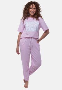 Set di abbigliamento da casa rosa chiaro composto da una maglietta cropped con una grafica a spirale bianca e pantaloni abbinati con vita elastica e polsini da jogger.