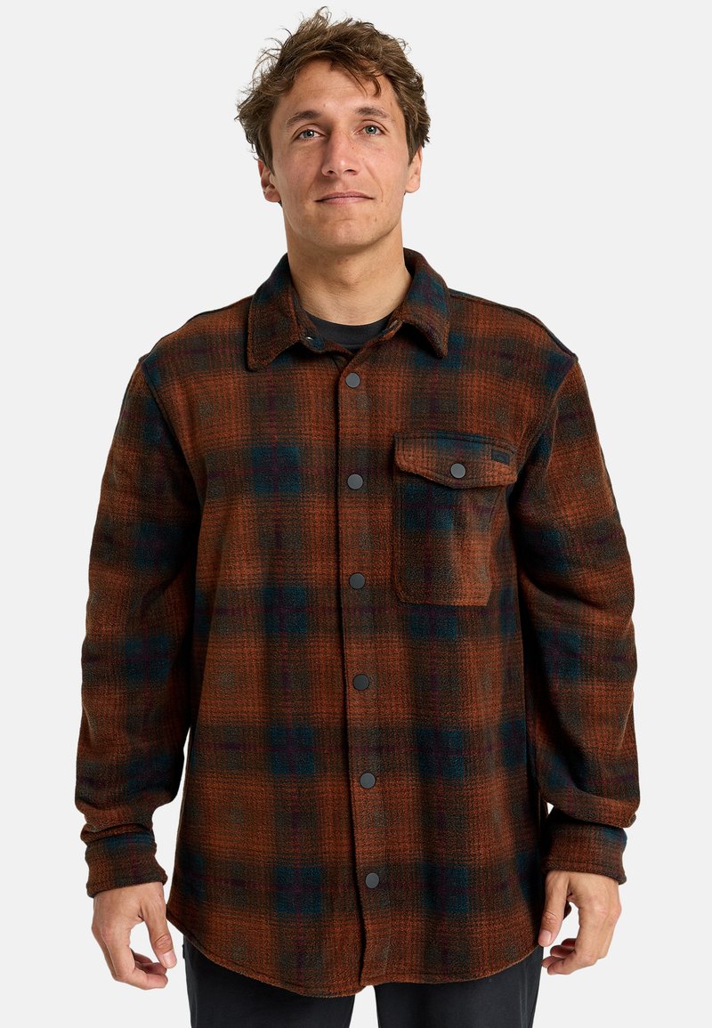 Karierte Flanellhemd in Braun, Marineblau und Grün. Verfügt über einen Button-Down-Kragen, eine einzelne Brusttasche und schwarze Druckknöpfe. Weicher Stoff.