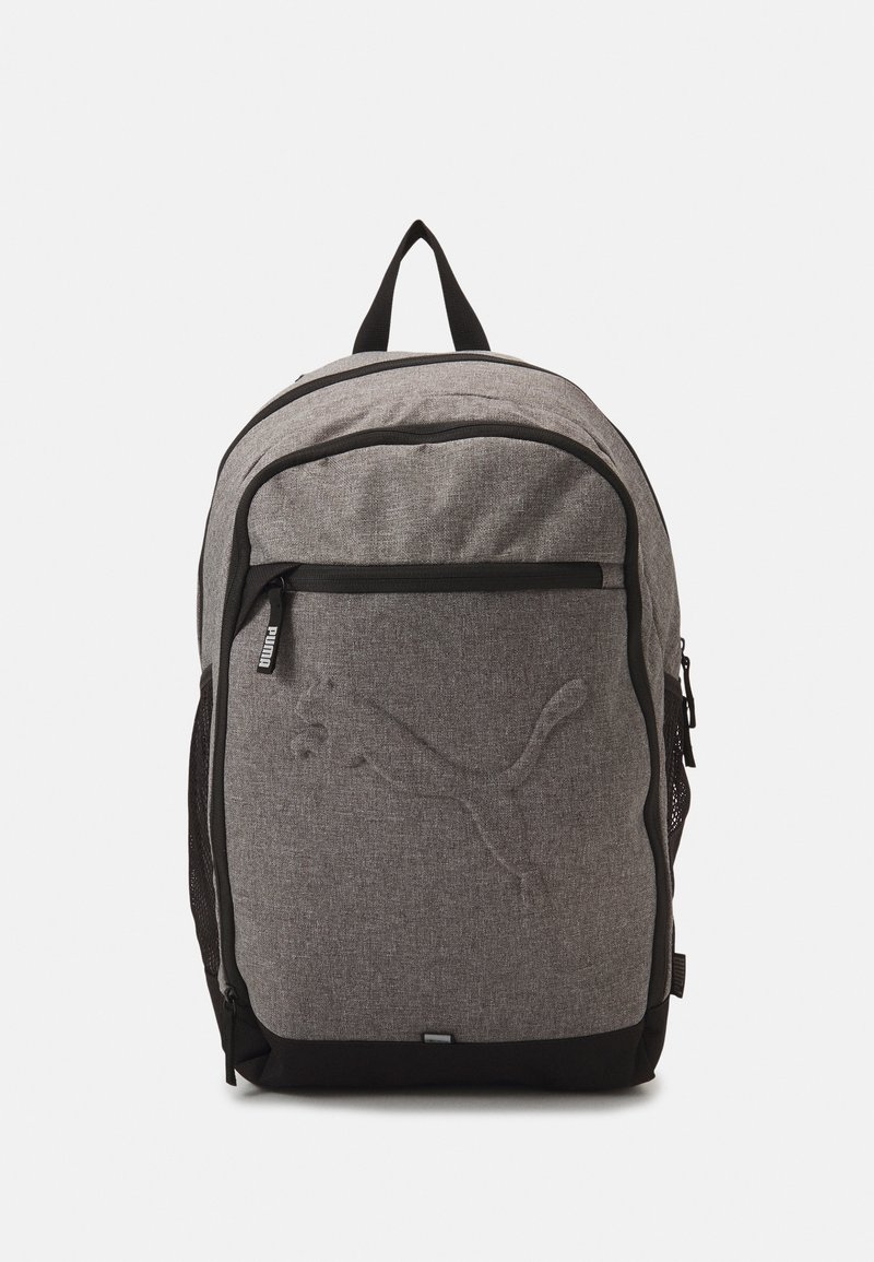 Šedý látkový batoh s přední kapsou na zip, černými akcenty a výrazným texturovaným logem. Obsahuje síťované boční kapsy a rukojeť na vrchu.