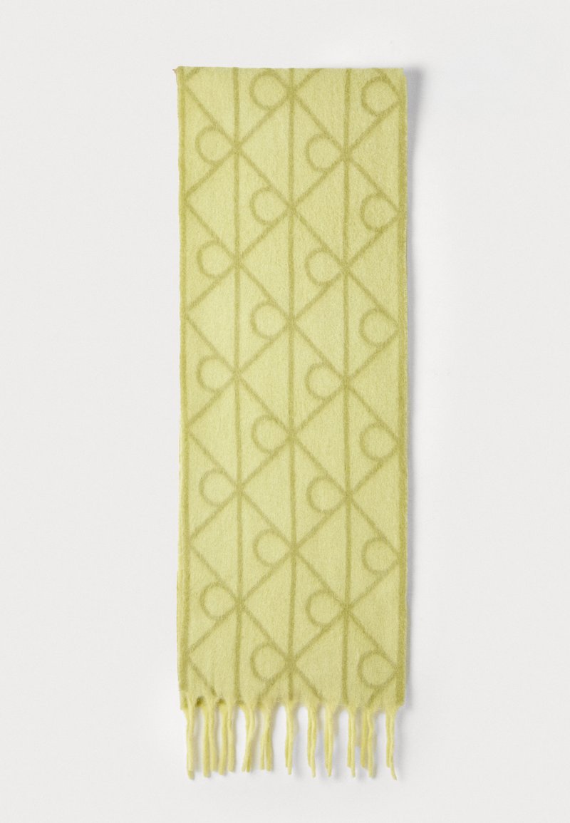 Écharpe verte en tissu doux et texturé, arborant un motif géométrique de diamants et de cercles, avec des bords frangés pour une touche supplémentaire.