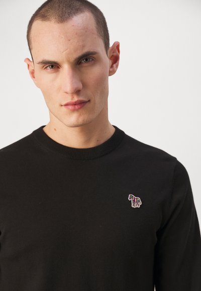 Μαύρο πλεκτό πουλόβερ με στρογγυλή λαιμόκοψη, με ένα μικρό, πολύχρωμο κεντημένο λογότυπο αλόγου στην αριστερή πλευρά του στήθους.