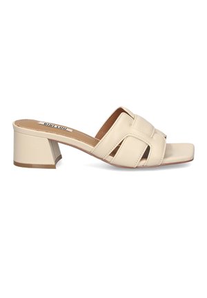 Mule in pelle beige con punta aperta, ampi cinturini incrociati e tacco a blocco, vista laterale su sfondo bianco.