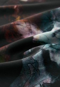 Texturovaná tkanina s abstraktním vzorem v tmavých tónech s akcenty modré, hnědé a fialové. Povrch vypadá hladce a vlnivě.