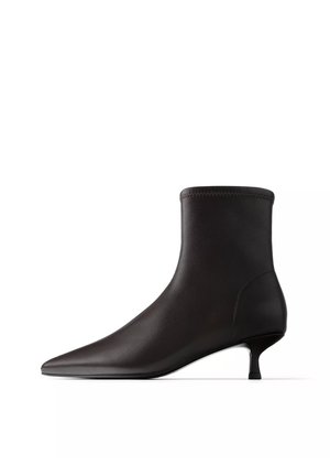 Czarny skórzany botek za kostkę z ostrym noskiem i niskim obcasem kitten, elegancki minimalistyczny design na białym tle.