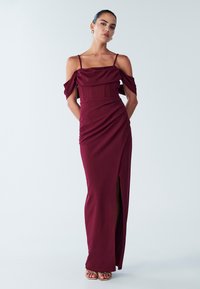 Punumärgitud burgundia värvi õlgadeta kleit, millel on vormitud ülakeha, drapeeritud tekstuur ja ülisäärtega lõhik, õhukeste rihmade ja sileda viimistlusega.