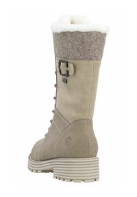 Beige leren laars met een vilten manchet, nepbontvoering, dubbele gespdetails en een gegroefde zool. Ontworpen voor warmte en grip.