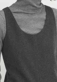 Robe en mélange de laine gris foncé avec encolure dégagée, superposée à un col roulé côtelé gris clair, mettant en valeur une texture douce et un design minimaliste.