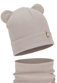 Berretto beige chiaro con orecchie d'orso e texture a coste. Include un collo coordinato, entrambi realizzati in tessuto morbido.