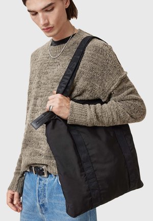 Borsa tote nera in nylon con manici testurizzati che mostrano un marchio in rilievo. La borsa presenta una chiusura con zip e una finitura morbida e opaca.