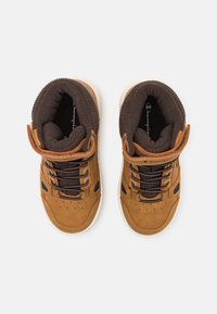 Sneaker alte imbottite marroni con lacci e strisce in Velcro, viste dall'alto su uno sfondo bianco semplice.