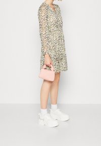 Šaty s květinovým vzorem a dlouhými rukávy, volný střih. V kombinaci s bílými chunky teniskami a malou růžovou kabelkou s žebrováním.