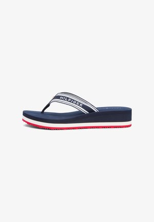 Navyblauwe sleehak flip-flop met zool met witte en rode strepen, stoffen band met de tekst "HILFIGER" in wit op een navyblauwe achtergrond.