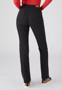 Jeans de mezclilla negra con pierna recta, talle alto y dos bolsillos traseros. Presenta un parche de cuero marrón claro en la cintura y detalles de costura mínimos.