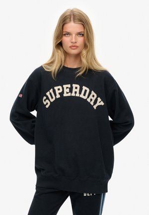 Sort sweatshirt lavet af bomuld, med oversized pasform, rund halsudskæring og "SUPERDAY" logo i cremefarve. Lange ærmer med logodetalje på manchetterne.