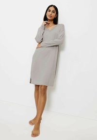 Vestido de noche gris de manga larga con escote en V y bordado de encaje. Tejido suave, hasta la rodilla, con aberturas laterales para mayor comodidad en el movimiento.