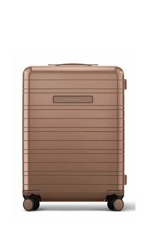 Hard-shell bronze suitcase with horizontal ridges, four black spinner wheels, and a recessed handle on the front side.