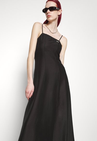 Čierna saténová maxi šaty s tenkými ramienkami a priliehavým korzážom, s hladkou textúrou a minimalistickým dizajnom. Doplnené detailom s logom.
