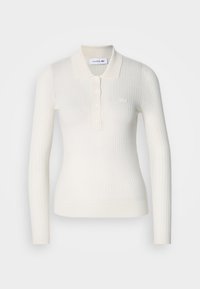 Csíkozott fehér, hosszú ujjú pólóing, galléros nyakkal, háromgombos szabással és Lacoste logóval a mellkasán. Sima textúra.