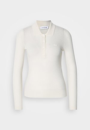 Ribbet hvit langermet polo med kragehals, tre-knappers placket og Lacoste-logo på brystet. Glatt tekstur.