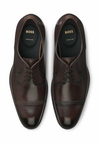 Scarpe da cerimonia in pelle marrone con finitura liscia, design con lacci, punta arrotondata e una sottile decorazione brogue lungo i bordi.