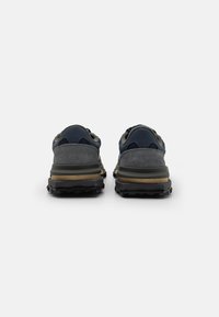 Scarpe da trekking blu e grigie con tomaia in suede e materiale sintetico, suole nere robuste e collari imbottiti. Progettate per comfort e aderenza.