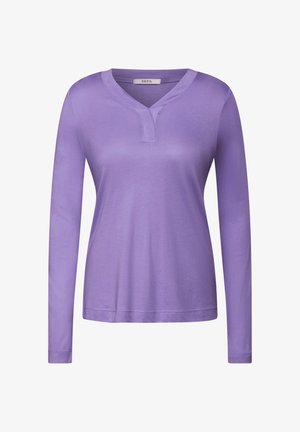 Top lavande à manches longues avec un col en V et des détails de couture au niveau du col, fabriqué en tissu doux, affichant une coupe décontractée.