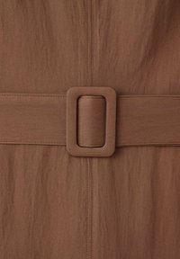 Bruine stoffen riem met een brede rechthoekige gesp. Het materiaal heeft een gladde textuur en de riem toont subtiele stiksel-details.