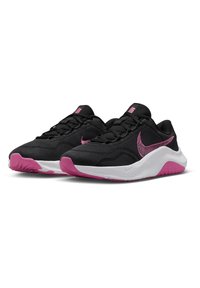 Chaussures de sport noires avec une tige en mesh, accents roses et semelle blanche. Présente un motif texturé et un logo sur le côté. Conception lacée.