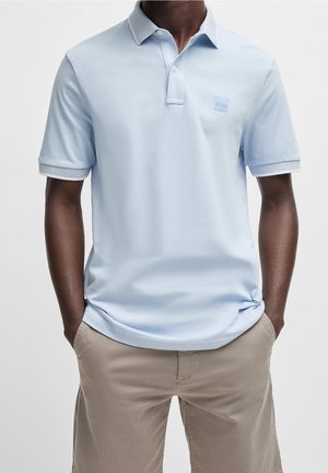Himmelblaues Polohemd mit kurzen Ärmeln, ausgestattet mit einer Drei-Knopf-Leiste und einem dezenten Kontrastbesatz am Kragen. Logo auf der Brust.