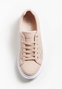 Baskets synthétiques rose clair avec une texture lisse, semelle blanche et motif latéral décoratif perforé. Œillets argentés et logo de la marque sur la languette.