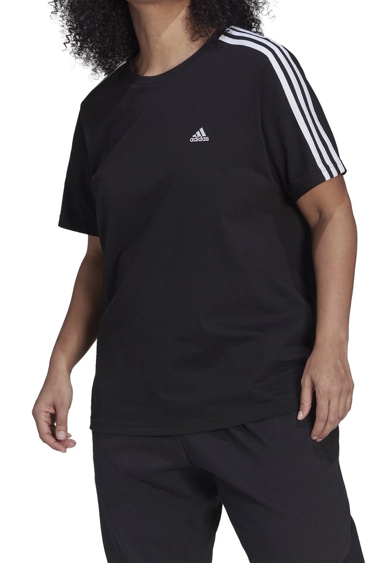 Svart bomulls-t-shirt med rund halsringning, korta ärmar och tre vita ränder längs axlarna. Liten vit logotyp på bröstet.